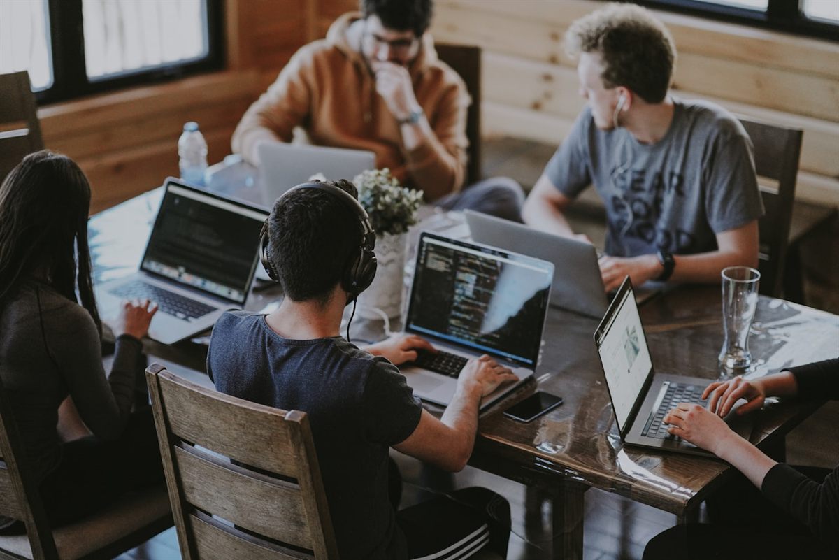 A software development team collaborating on laptops around a table